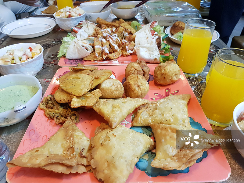 多种亚洲炸食品和油条与橙汁一起在家中餐桌上享用，适合在斋月的开斋时刻。图片素材