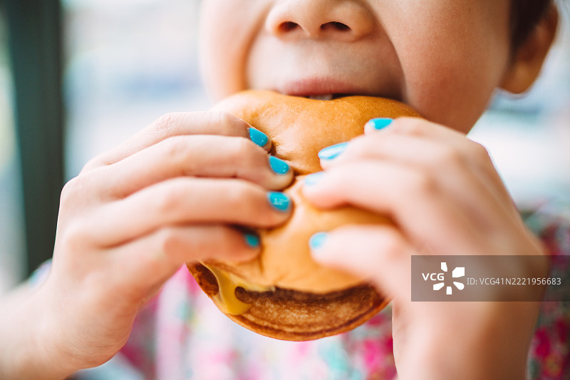 孩子近距离享用汉堡，五彩斑斓的指甲引人注目图片素材