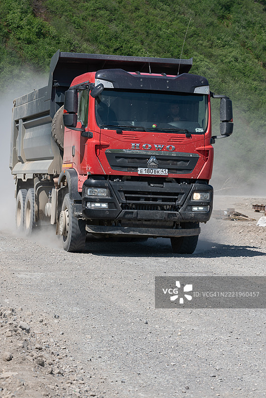 中国重汽HOWO自卸车在乡村的碎石路上行驶。图片素材