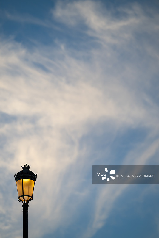 街灯在黄昏时分照亮天空中的轻柔云朵图片素材
