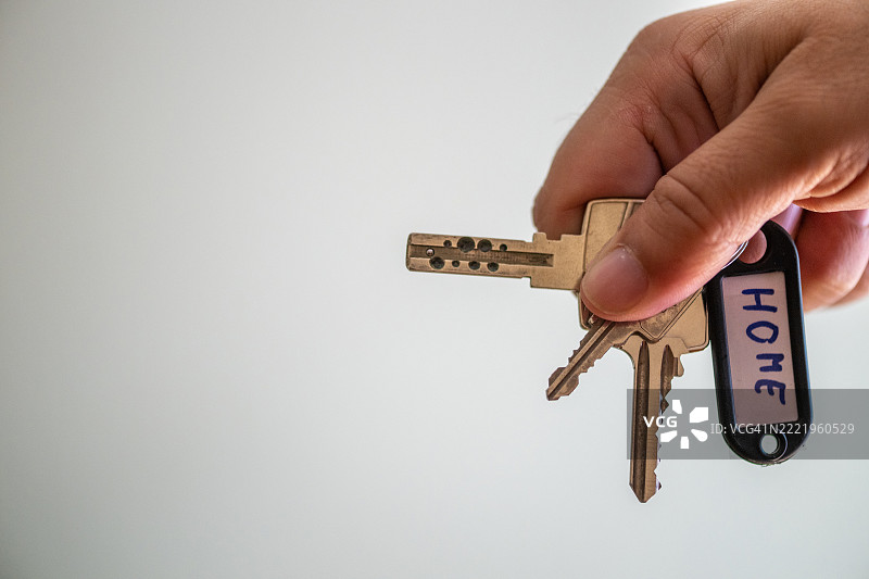 手握房屋钥匙，白色背景上的家标签图片素材