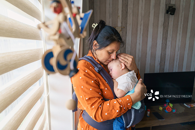 拉丁美洲母亲拥抱着熟睡的唐氏综合症宝宝图片素材