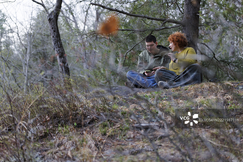母亲与孩子的鸟类识别。红头发的女性帮助自闭症年轻人使用智能手机识别物种和鸟鸣声，地点在宾夕法尼亚州贝尔茨维尔州立公园。图片素材