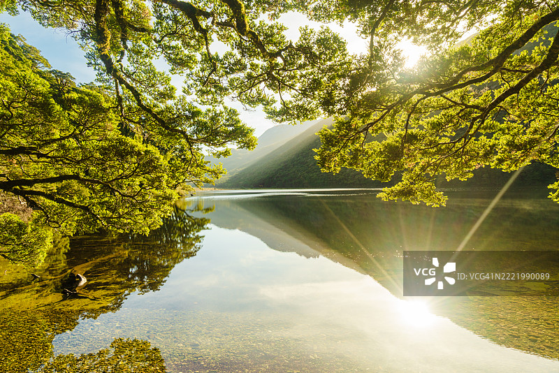 郁郁葱葱的山丘沿着宁静的水体。图片素材