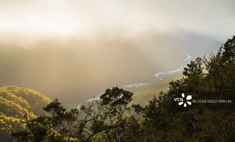 金色的山丘和雾气弥漫的溪流。图片素材