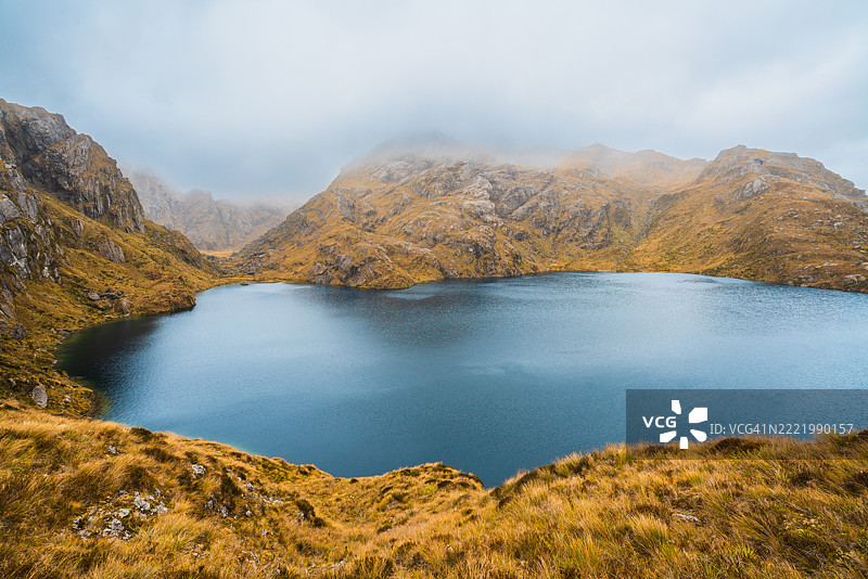 宁静乡村山丘中的平静湖泊。图片素材