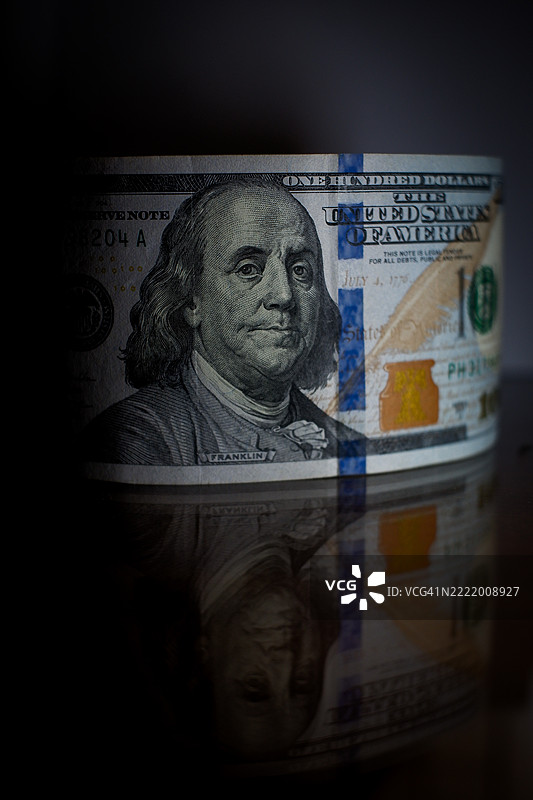 黑色背景下的一百美元钞票特写及其反射图片素材