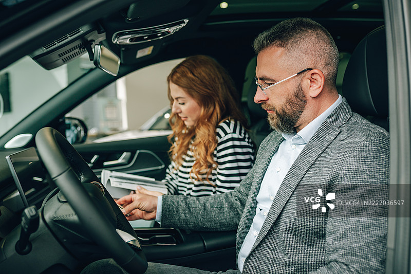 情侣在汽车经销商处选择新车，视角来自车内图片素材