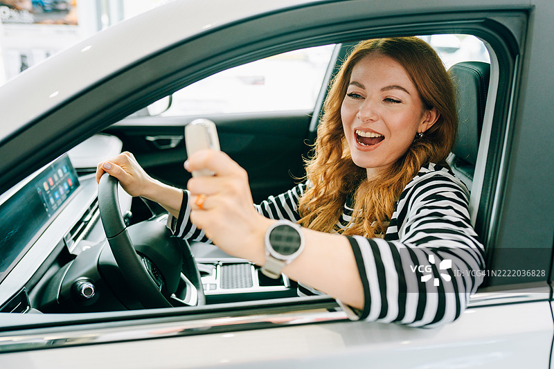 开心的女人拿着新车钥匙，驾驶着新车图片素材