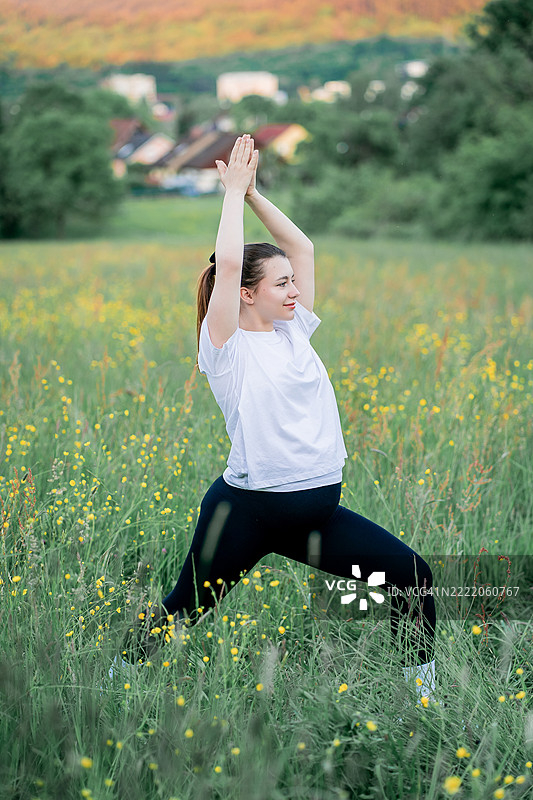 穿着运动服的年轻孕妇在城市外的街道上做瑜伽。公园里的康复运动。母亲身份。图片素材