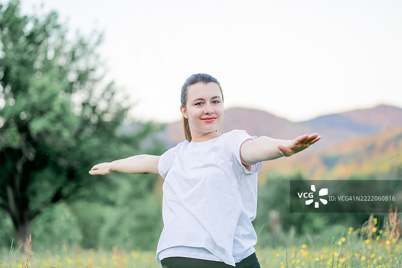 穿着运动服的年轻孕妇在城市外的街道上做瑜伽。公园里的康复运动。母亲身份。图片素材