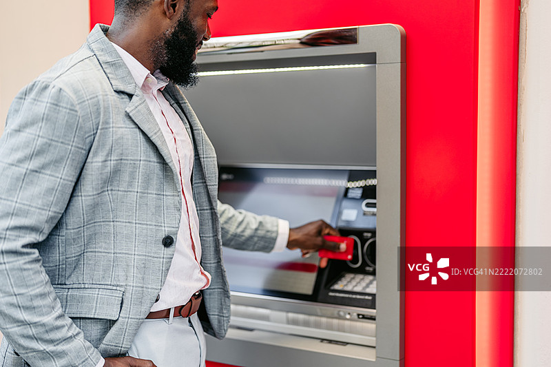 中年非裔美国商人在迈阿密市中心的ATM机上使用信用卡取款图片素材
