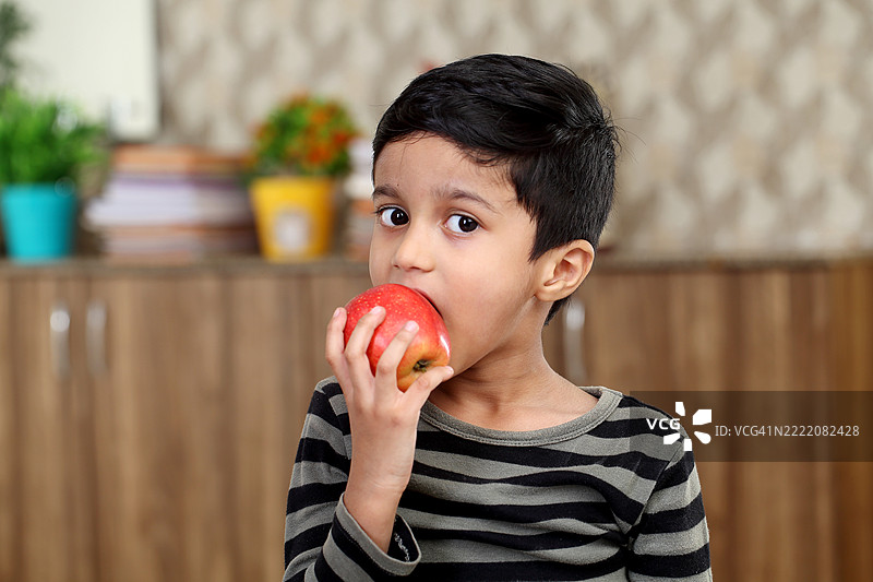 放松的小学生在吃红苹果图片素材