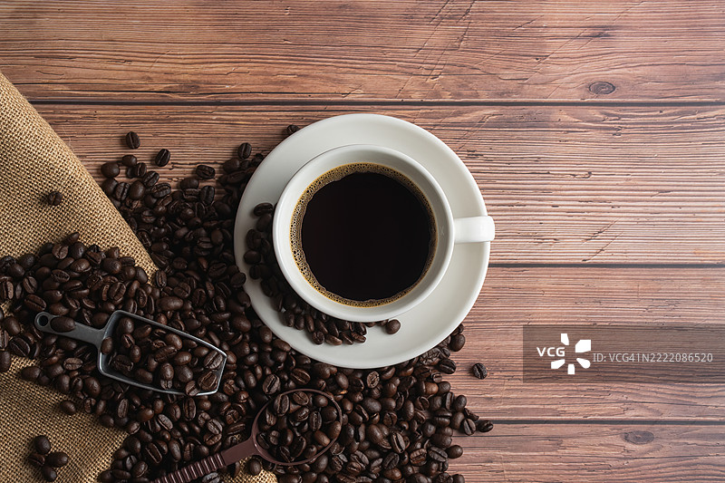 咖啡杯装饰的平铺图，旁边有木勺盛着烘焙咖啡豆，放在木桌上。图片素材