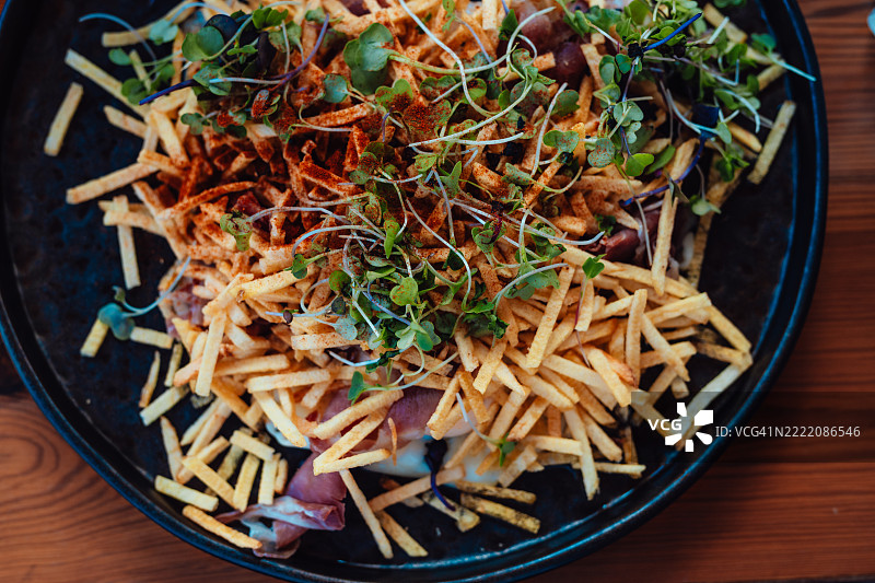 一盘西班牙小吃，火腿土豆条，刚刚在餐厅的木桌上上桌。图片素材