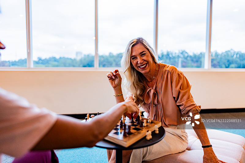 办公室里一位女商人与同事下棋的肖像图片素材