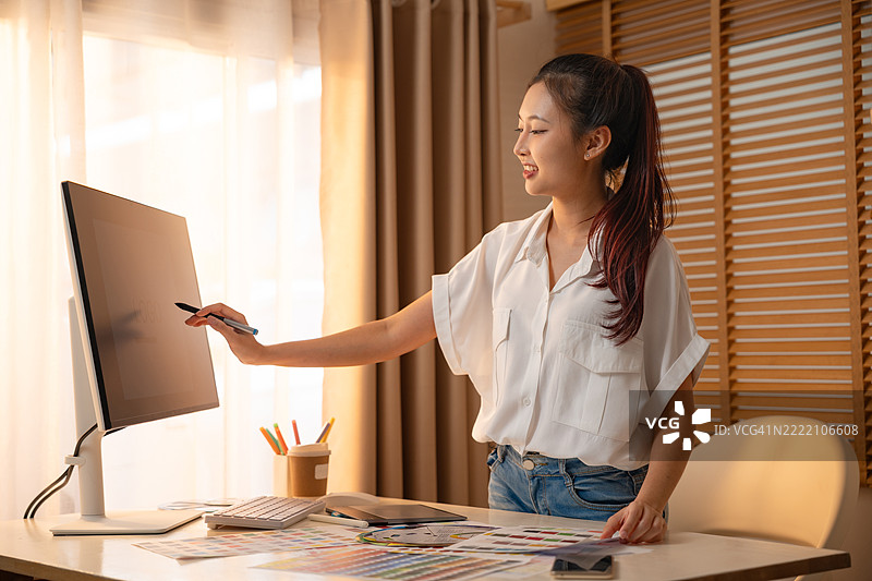 年轻的亚洲女性平面设计师在记录标志设计。色彩样本。艺术家在办公室的图形平板上绘画。平面设计师的创意编辑理念概念。图片素材