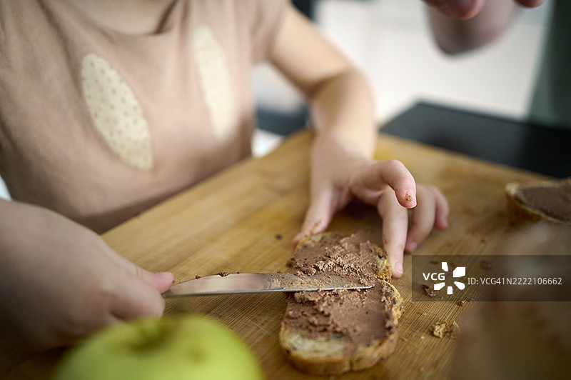 女孩在切菜板上涂抹面包的特写镜头图片素材