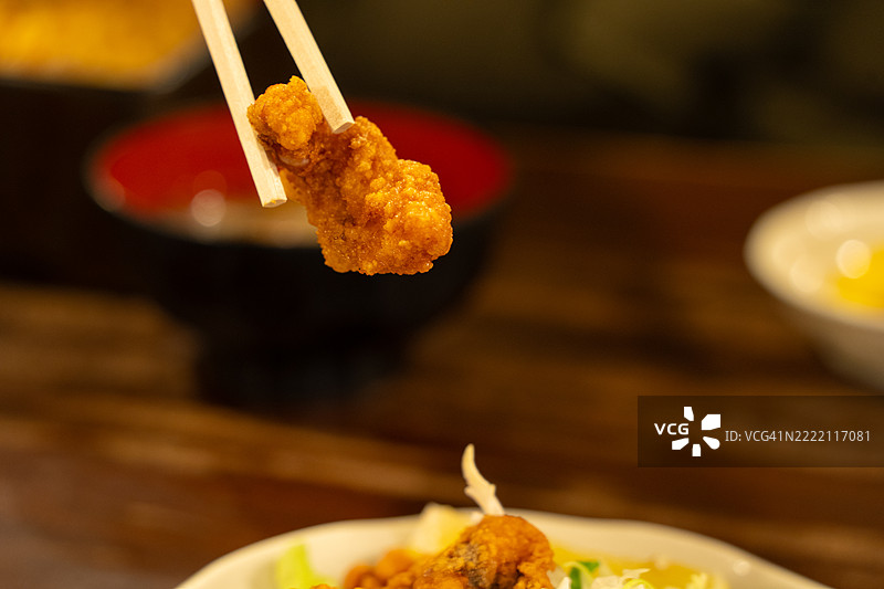 一个人正在用筷子夹起一块炸食。图片素材