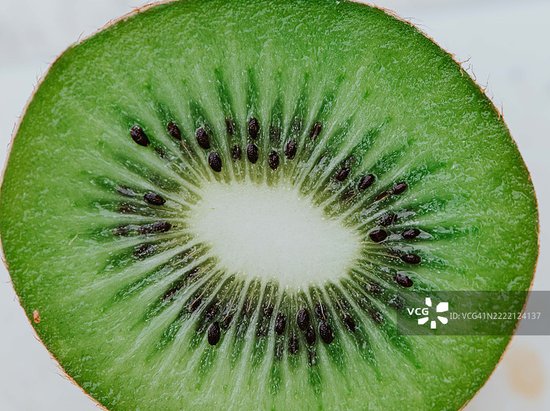 新鲜切片的猕猴桃，鲜艳的绿色果肉和细小的黑色种子，吸引地展示在白色背景上。图片素材