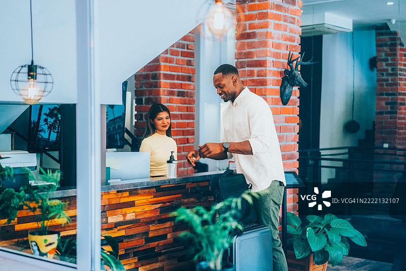 商人在酒店接待处办理入住并消毒双手图片素材