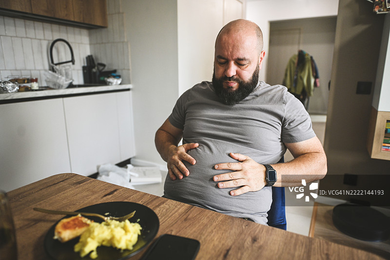 男人喜欢吃东西，因暴饮暴食而腹痛图片素材