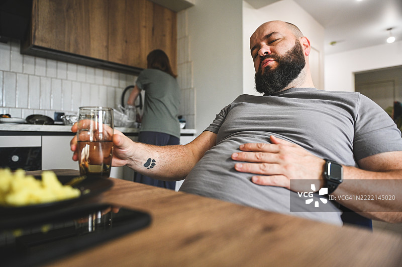 男人喜欢吃东西，因暴饮暴食而肚子疼。图片素材
