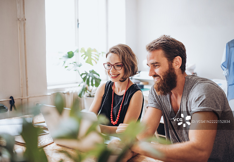 两位同事在他们的缝纫工作室讨论一个新订单。图片素材