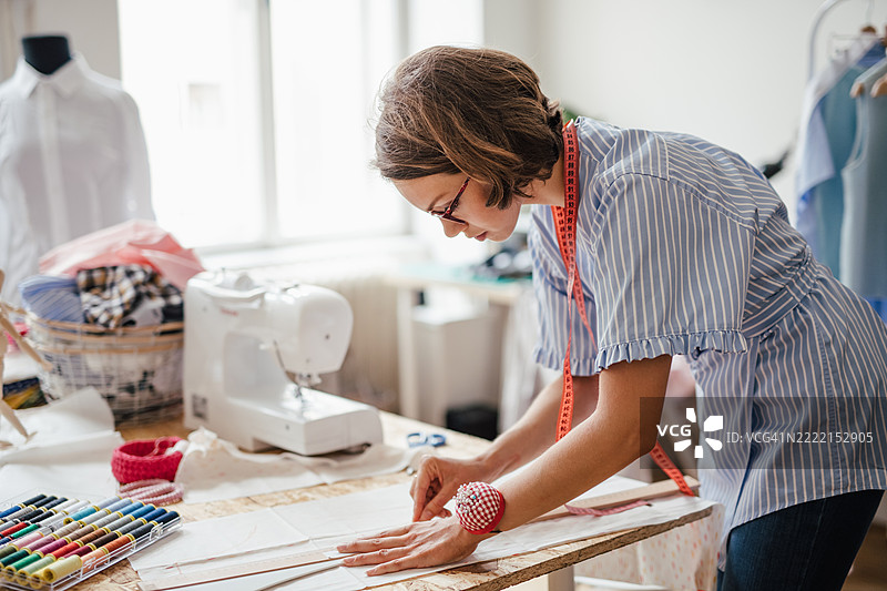 缝纫师在为新的时尚设计准备和测量面料的特写镜头图片素材