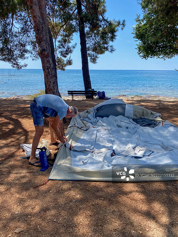 成熟男性在海边搭建充气帐篷图片素材