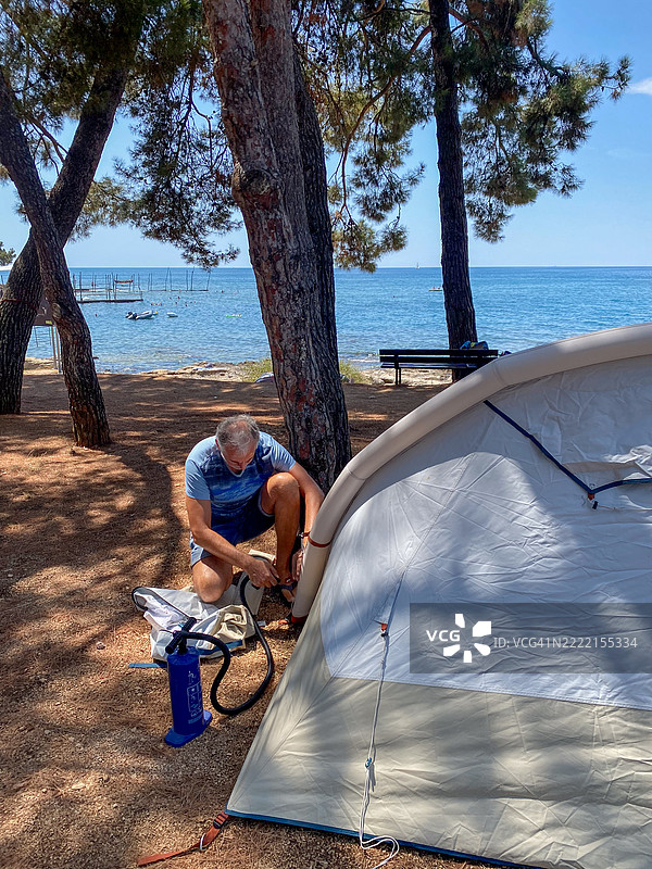 成熟男性在海边搭建充气帐篷图片素材
