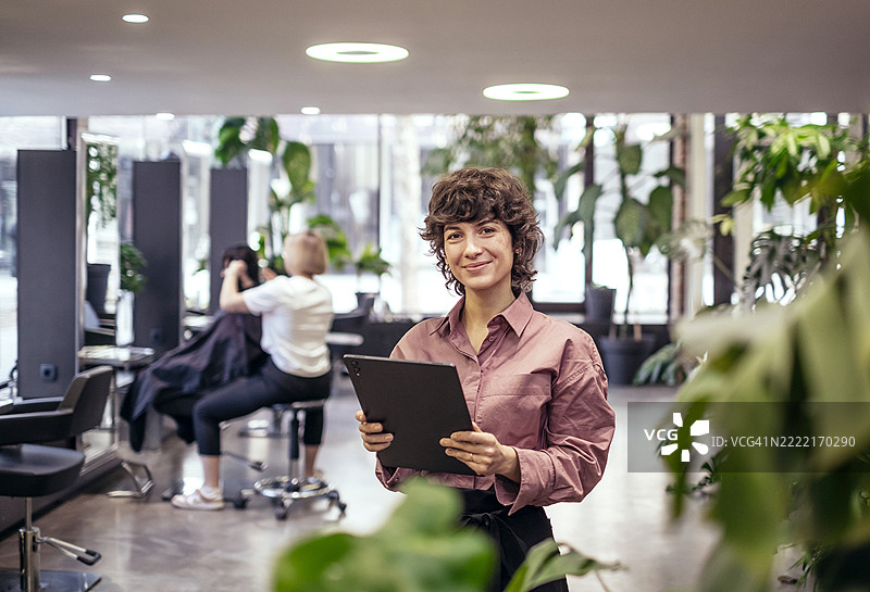 自信的年轻女性发型师在现代室内环境中与植物相伴图片素材