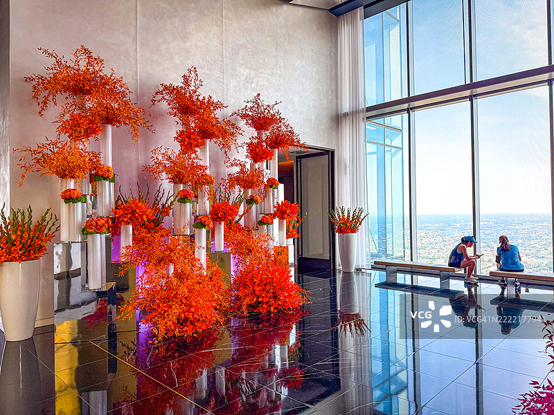 人们在费城四季酒店的天空高处入口处的长椅上放松，查看手机。图片素材