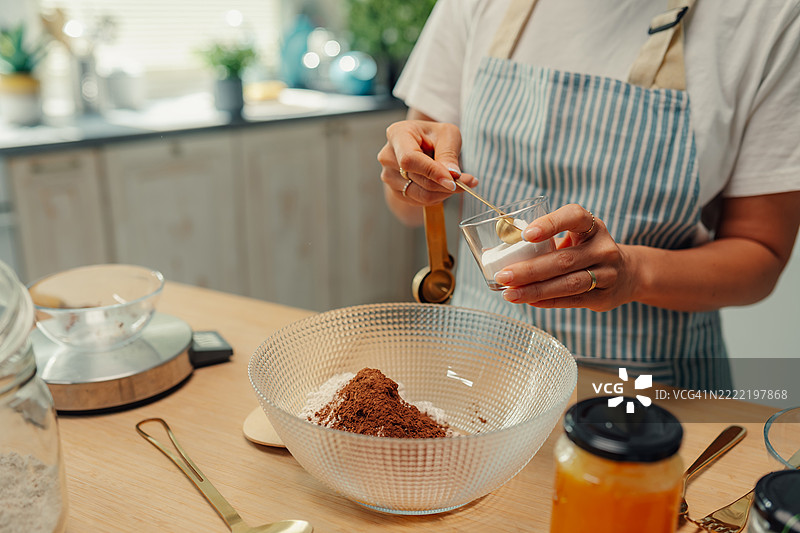 女人在玻璃碗中向面粉和可可混合物中添加小苏打图片素材