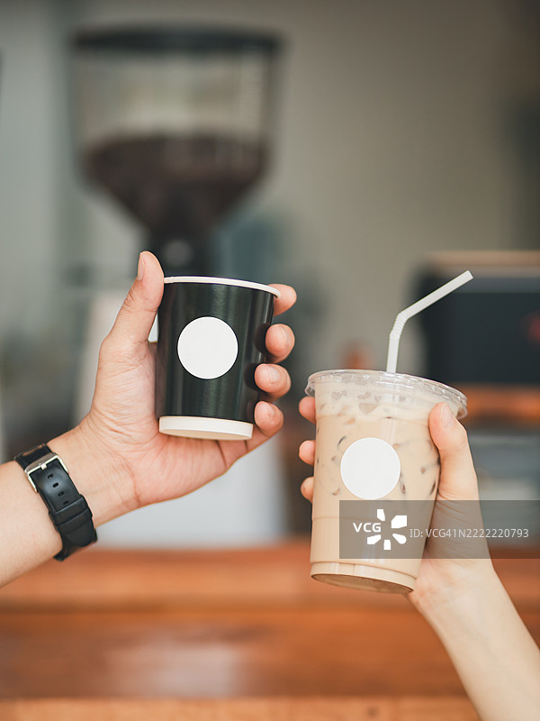 手中拿着咖啡纸杯和冰咖啡图片素材