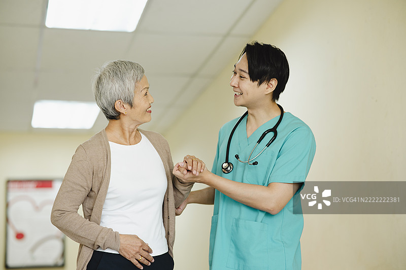 友好的医疗专业人士在诊所帮助老年患者行走图片素材