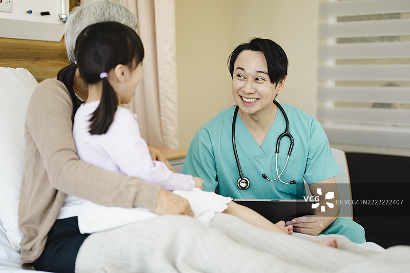 微笑的医生在医院病房中与孩子和祖父母互动图片素材