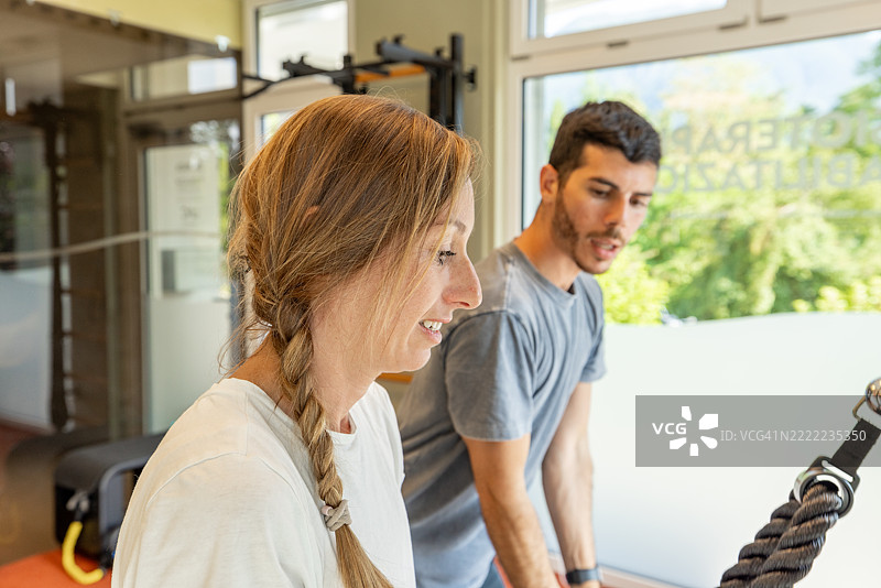 女性在健身房与教练一起进行拉索训练图片素材