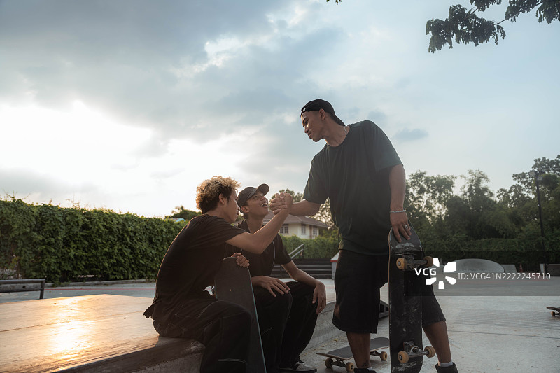 年轻的亚洲滑板少年们在滑板公园里坐在一起图片素材