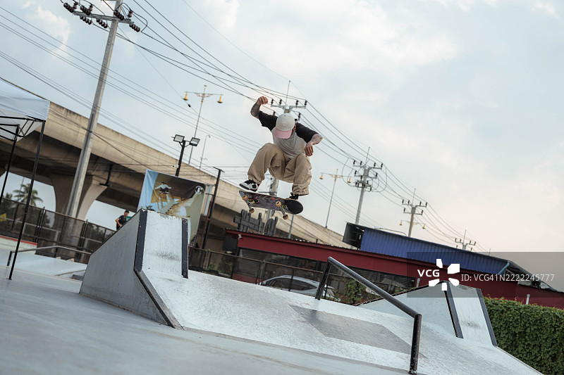 亚洲男性运动员在滑板比赛中进行滑板跳跃。图片素材