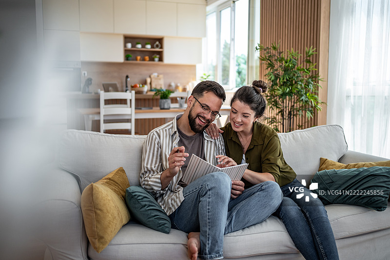 幸福的情侣在家沙发上一起阅读一本书图片素材