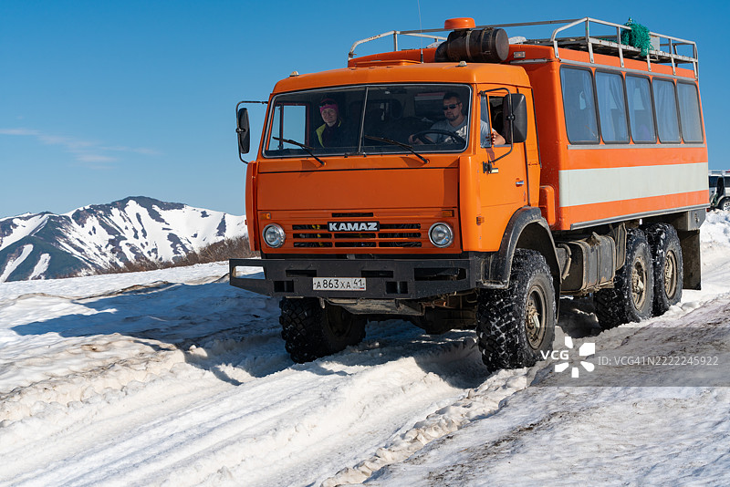 一辆俄罗斯越野客运探险卡车，卡玛斯，正在雪山公路上驶向热门旅游目的地。图片素材