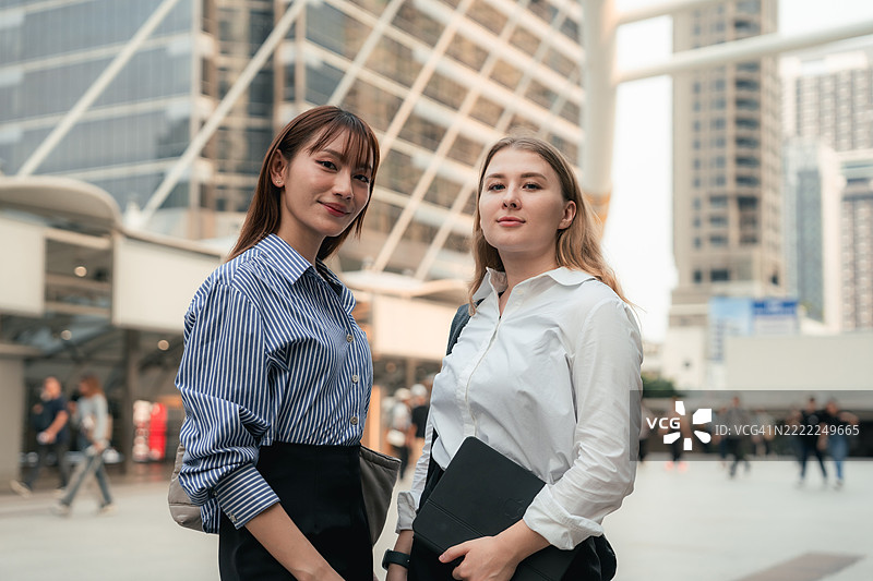 两位自信的女商人在繁忙的城市中前往工作，散发出现代领导力的活力。图片素材