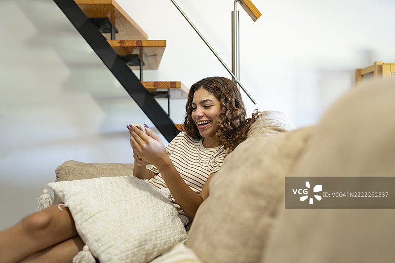 少女坐在沙发上使用智能手机图片素材