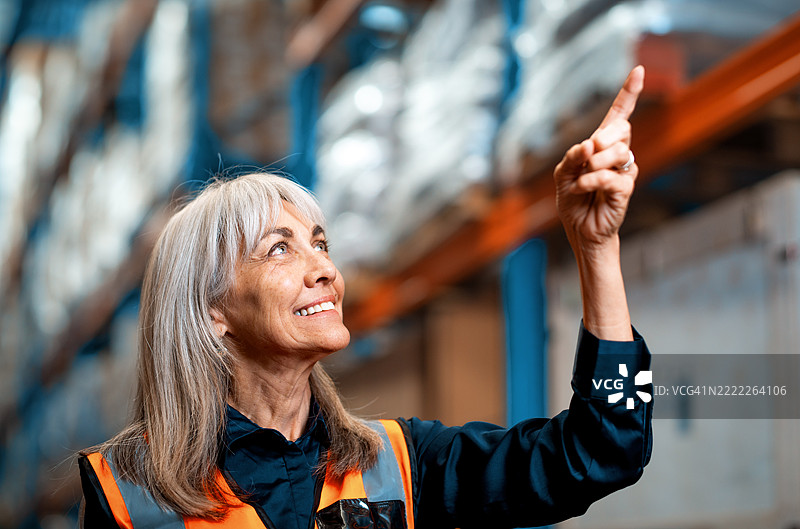 微笑的物流专业人士在仓库环境中检查库存货架图片素材