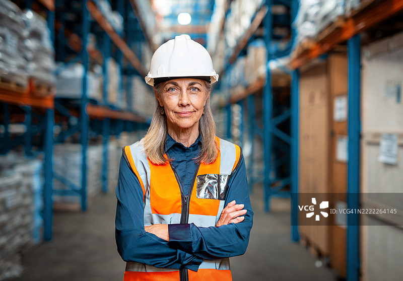 自信的女性物流经理在仓库环境中穿着安全装备和安全帽图片素材