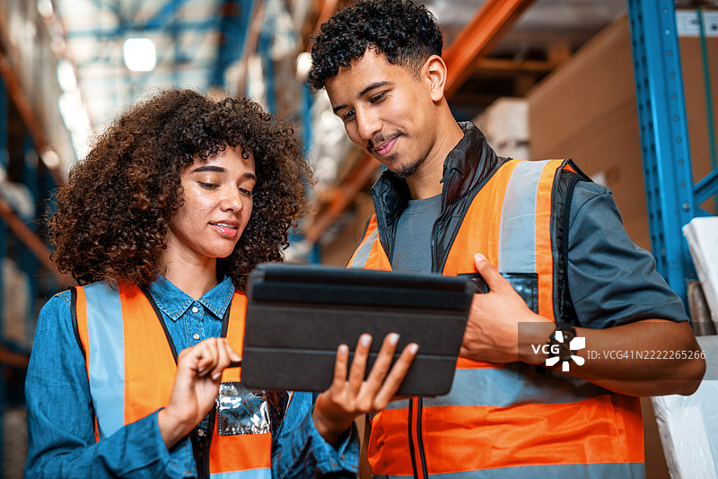 仓库工人在配送中心协作使用平板电脑进行库存管理图片素材