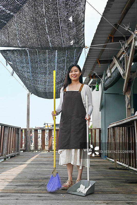 户外清洁：女性在乡村环境中扫垃圾图片素材