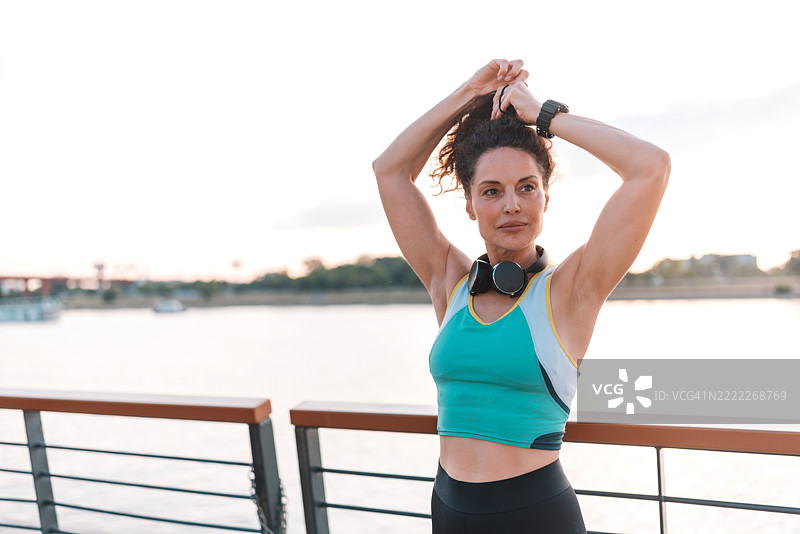 专注的女性在日落时分水边锻炼图片素材