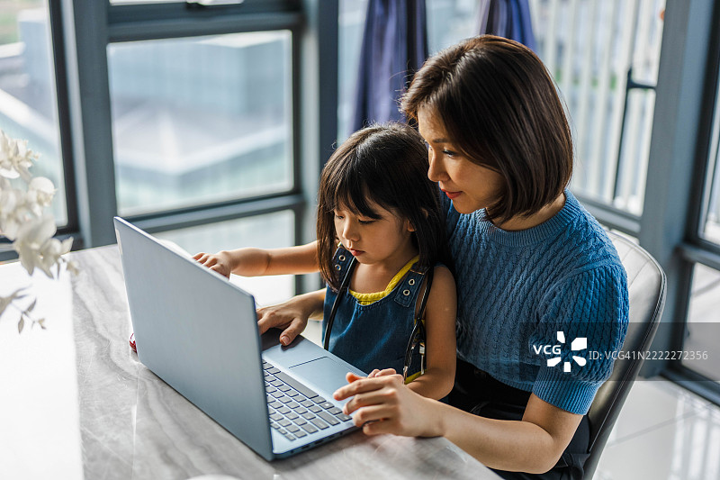 一位母亲在家里帮助她的小女儿做作业。图片素材